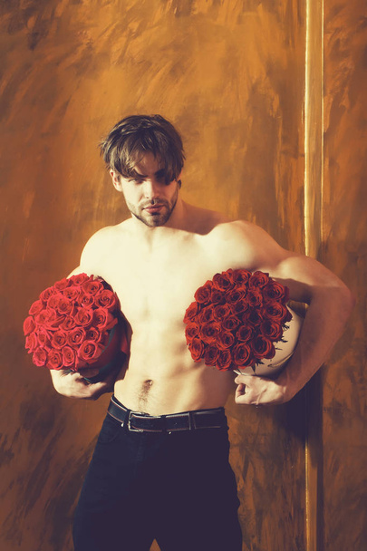 bearded muscular man with sexy body holds red rose box - 写真・画像