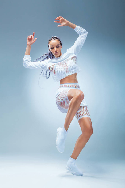 Attractive excited fitness girl dancer in sportwear dance isolated over blue background. Fashion and livestyle concept. - Photo, Image