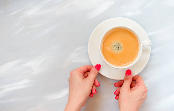 Woman hands holding coffee mug or cup on colorful table. Photograph taken from above, top view with copy space - 写真・画像