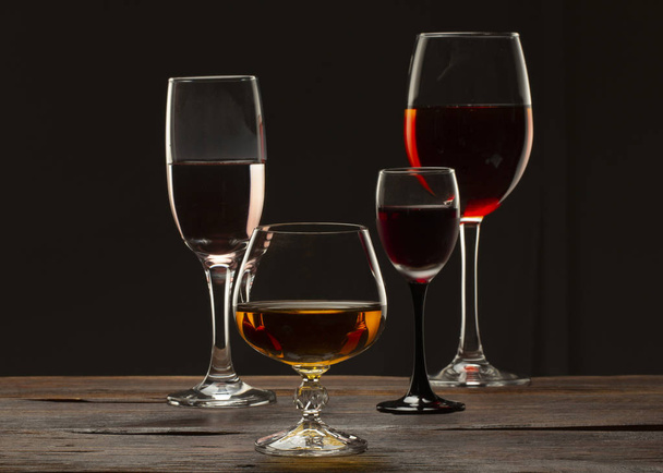 Imagen de naturaleza muerta de vidrio Una copa de vino tinto en una copa sobre un fondo negro de cerca
 - Foto, imagen