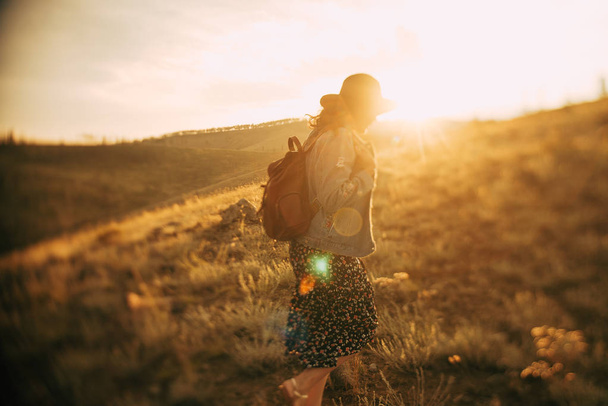 дівчина з рюкзаком, що ходить на полі на заході сонця
 - Фото, зображення