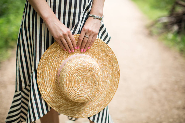 girl holding a straw hat in hands - Foto, Imagen