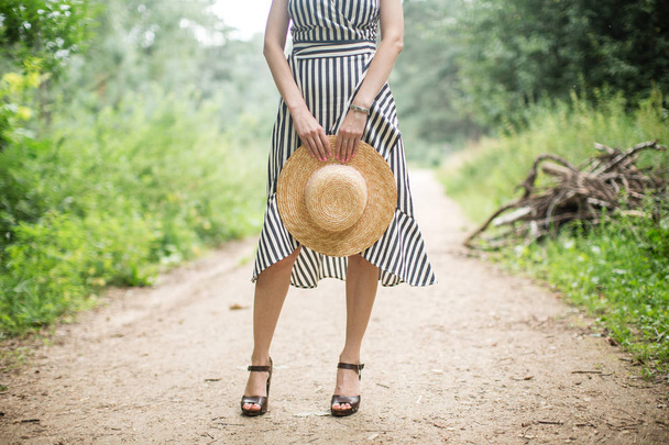girl holding a straw hat in hands - Foto, imagen