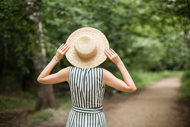 girl in a hat and dress walking in the woods - Foto, Imagen