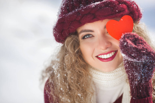 Retrato de mujer joven atractiva al aire libre en invierno mostrando el corazón de papel
 - Foto, imagen