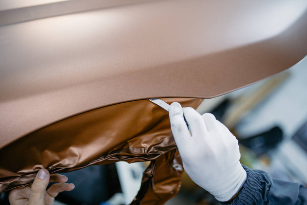 Car wrapping specialist putting vinyl foil or film on car. Selective focus. - 写真・画像
