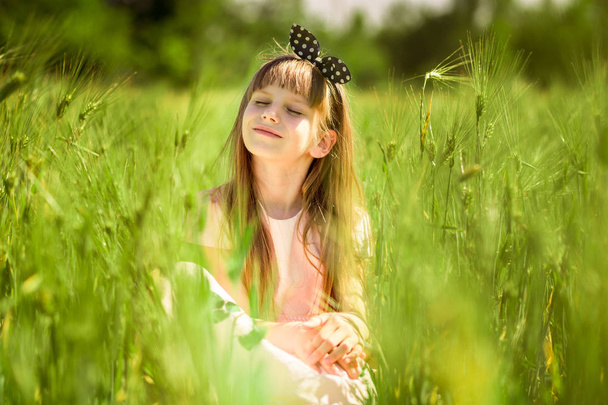 Portrait of beautiful little girl in middle of green summer field - Фото, изображение