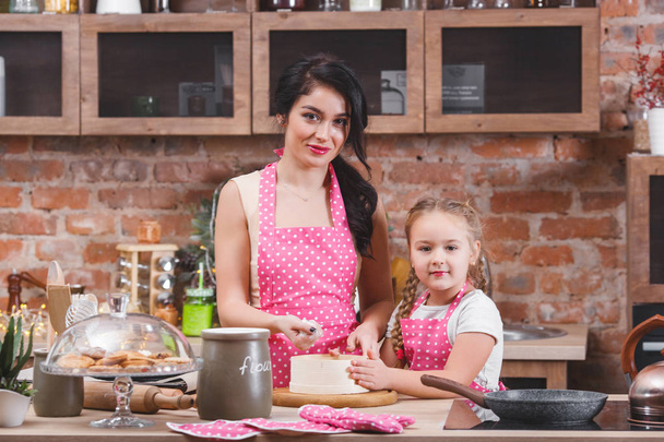 Jeune belle mère et sa petite fille cuisinent ensemble à la cuisine
 - Photo, image
