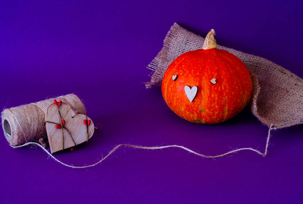 Symbol of HALLOWEEN is Orange pumpkin using the stamp  wooden heart, isolated on purple background,copy space, closeup, - Foto, Imagem