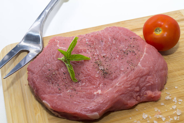 steak de boeuf cru sur planche à découper avec tomates cerises et feuilles de basilic
 - Photo, image