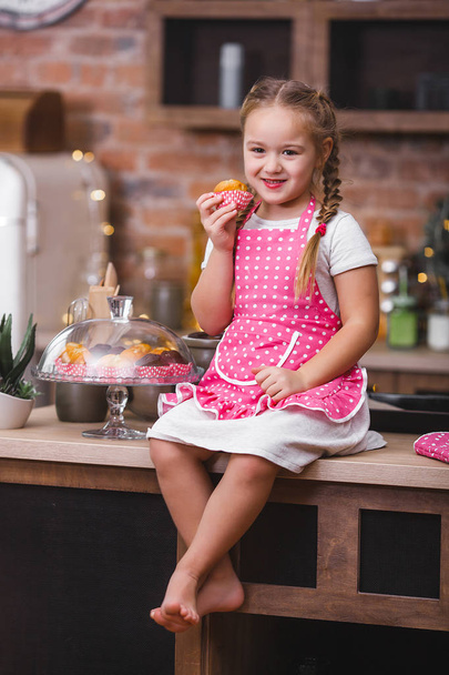 Little cute girl in the kitchen eating cupcakes - Valokuva, kuva