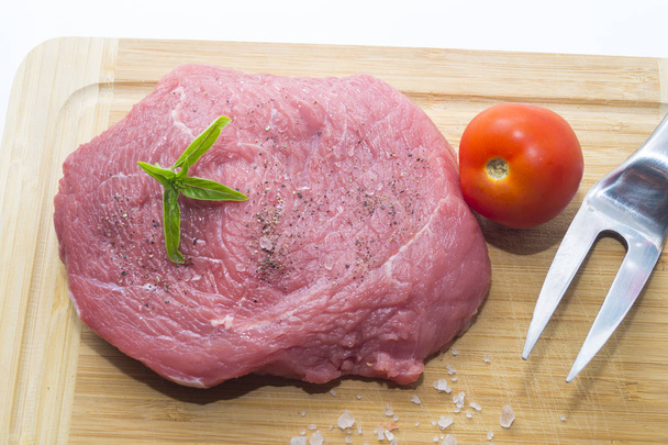 сирий яловичий стейк на обробній дошці з вишневими помідорами та листом базиліка
 - Фото, зображення