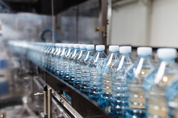 Palackozó üzem - Vízpalackozó sor tiszta forrásvíz kék palackokká történő feldolgozásához és palackozásához. Szelektív fókusz.  - Fotó, kép