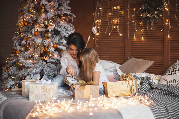 Young pretty mother and her little daughter sharing Christmas presents - Photo, Image