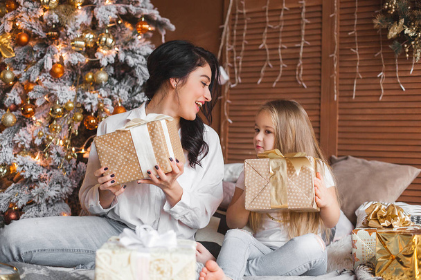 Joven bonita madre y su pequeña hija compartiendo regalos de Navidad
 - Foto, imagen