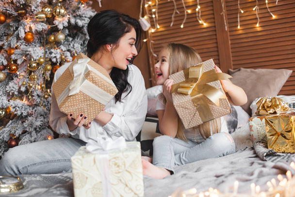 Jeune jolie mère et sa petite fille partageant des cadeaux de Noël
 - Photo, image