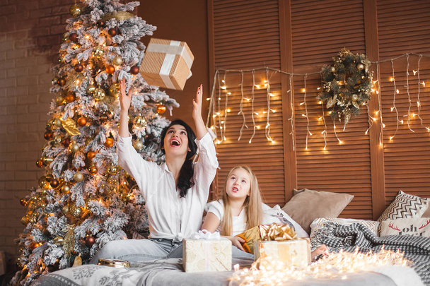 Young pretty mother and her little daughter sharing Christmas presents - Valokuva, kuva
