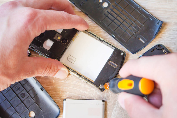 Een man is het repareren van een smartphone - Foto, afbeelding