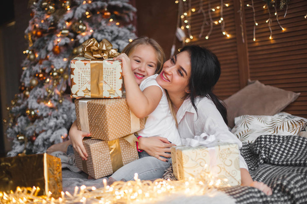 Молодая красивая мать и ее маленькая дочь делятся рождественскими подарками
 - Фото, изображение