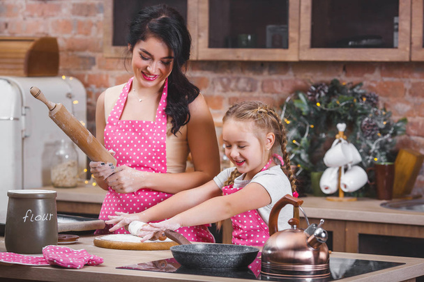 Nuori kaunis äiti ja hänen pieni tyttärensä ruoanlaitto yhdessä keittiössä
 - Valokuva, kuva