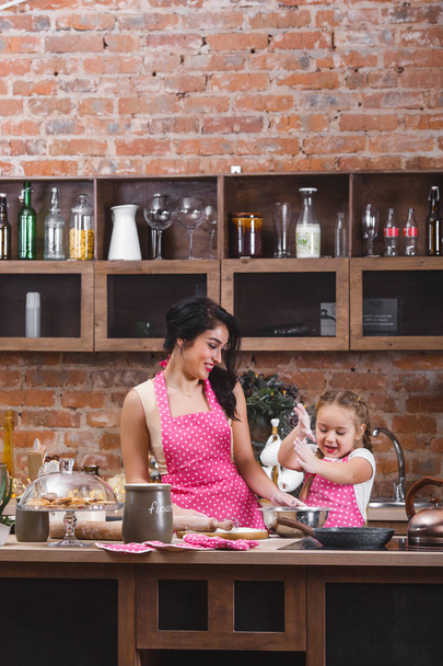 Молода красива мати і її маленька дочка готують разом на кухні
 - Фото, зображення