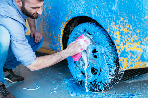 homem limpando carro com esponja usando espuma azul, carro detalhando (ou valeting) conceito. Foco seletivo
. - Foto, Imagem