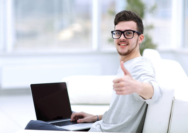 modern young sitting in front of the open laptop and showing thumb up - Фото, изображение