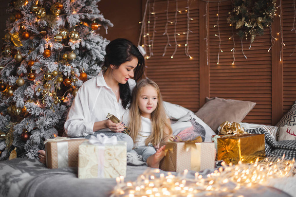 Giovane bella madre e la sua piccola figlia condividere regali di Natale
 - Foto, immagini