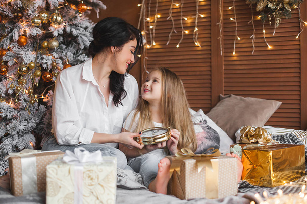 Молодая красивая мать и ее маленькая дочь делятся рождественскими подарками
 - Фото, изображение