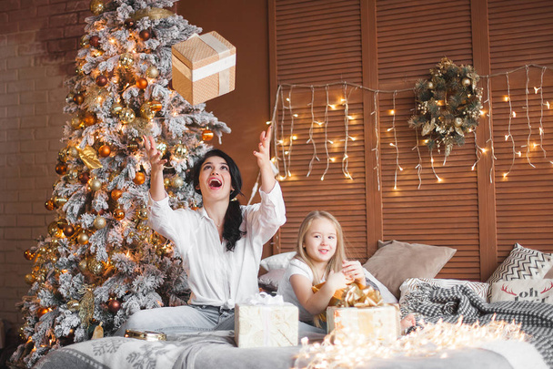 Joven bonita madre y su pequeña hija compartiendo regalos de Navidad
 - Foto, Imagen