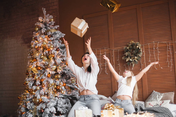 Young pretty mother and her little daughter sharing Christmas presents - Foto, imagen