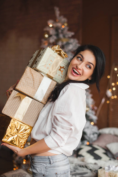 クリスマス プレゼントを保持している若い陽気な女性 - 写真・画像