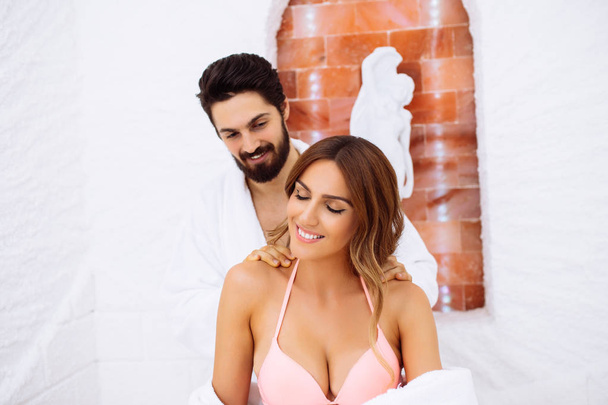 Young beautiful couple enjoying and relaxing in SPA center salt room - Photo, Image