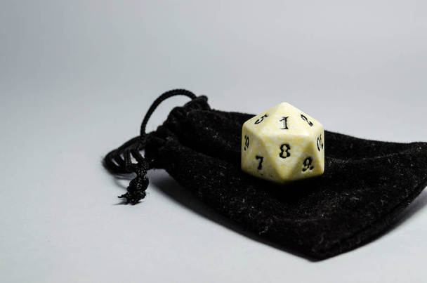 fehér húsz oldalú kocka, egy kis fekete pénztárca, fehér alapon a. Kocka, szerepet játszani a játékot, és dungeons és dragons. szemközti nézet. - Fotó, kép