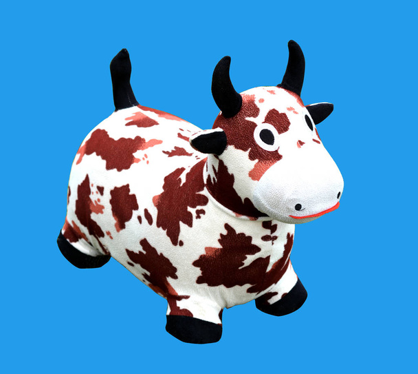 Vaca lechera de juguete aislada sobre fondo azul. Copiar espacio
 - Foto, Imagen