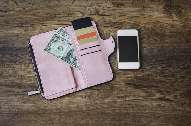 geld en korting kaarten in een open portemonnee en een telefoon tegen een grijze achtergrond - Foto, afbeelding