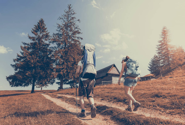 Mladý šťastný pár hikking s lůžkem v horách. Rodinné dobrodružství a koncept zdravého životního stylu - Fotografie, Obrázek