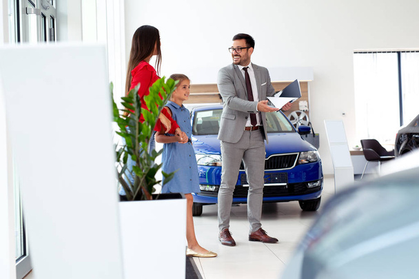 Family buying a new car in the car dealership saloon - Foto, imagen