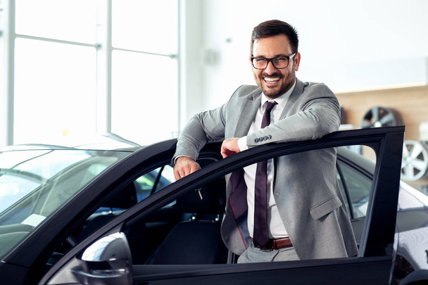 Successful businessman in a car dealership - sale of vehicles to customers - Foto, Imagen