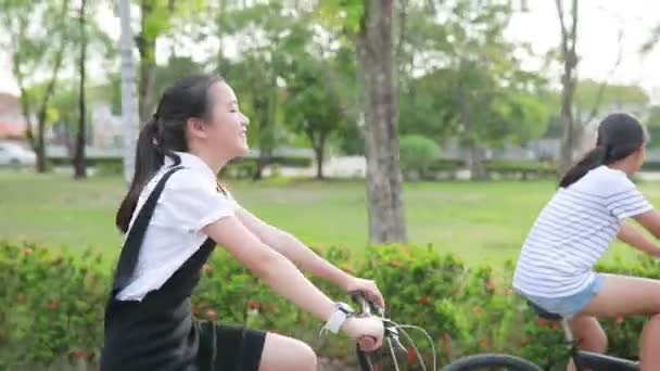 kaksi aasialainen teini ratsastus polkupyörän julkisessa puistossa
 - Materiaali, video