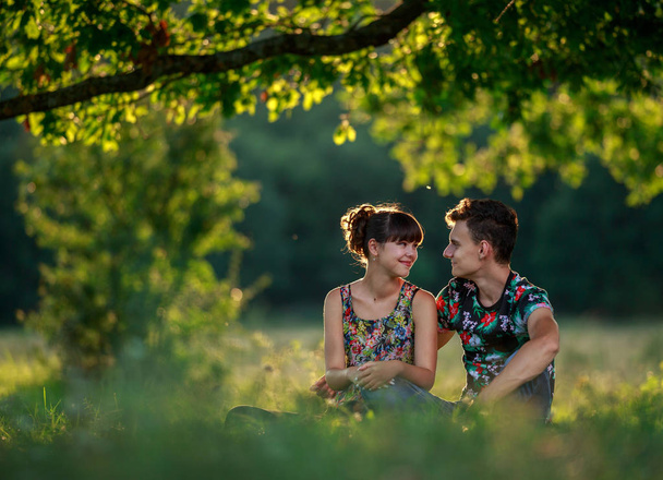 Happy young couple under a big tree at sunset - Foto, afbeelding