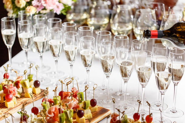 Cantinero vertiendo champán o vino en copas de vino sobre la mesa en el restaurante. solemne ceremonia de boda o feliz año nuevo banquete
 - Foto, imagen