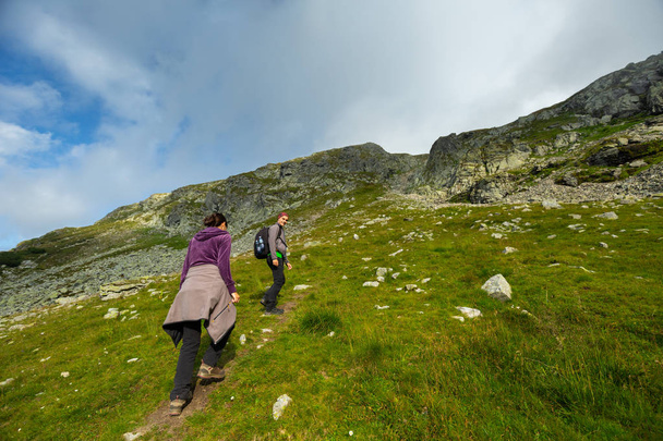 Young couple in holiday hiking into mountains at daytime - Foto, imagen