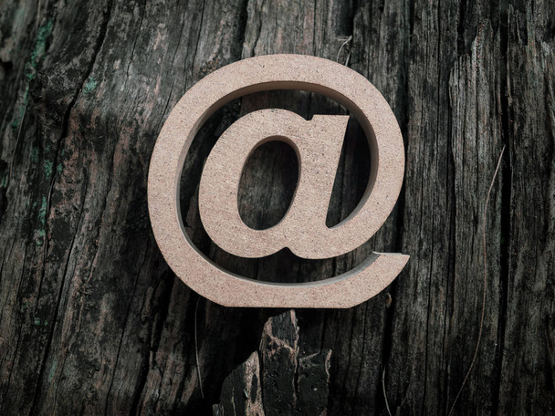Símbolo de dirección de correo electrónico de madera, icono de arroba sobre fondo de textura de madera seca vieja. Marketing por correo electrónico concepto de Internet, tecnología y medio ambiente en línea
. - Foto, imagen