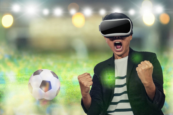 Молодой человек с наушниками Виртуальный рад приветствовать футбольные матчи на фоне размытого
. - Фото, изображение