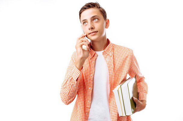 Teen guy talking on phone, with books in hand, in photo Studio on white background - Фото, изображение