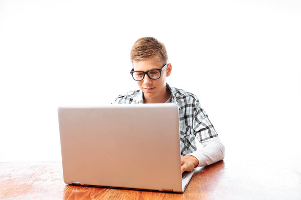 Mladý muž sedí u stolu s přenosným počítačem a psaní textových zpráv nebo mluví o videu, ve studiu - Fotografie, Obrázek