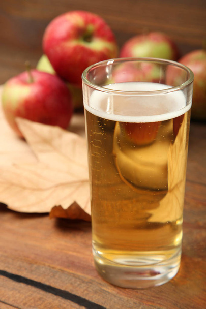 Apple cider in een glas op een bruin houten achtergrond. - Foto, afbeelding