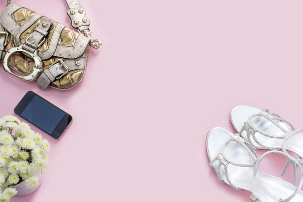 Modern divat kiegészítők fiatal nők cipő táska telefon szerkentyű rúzs kozmetikumok bouquet virágok rózsaszín háttér. - Fotó, kép