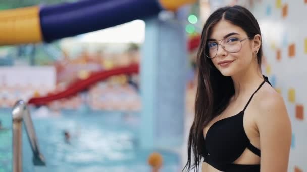 Sexy young women in black swimsuit posing in pool. Portrait of an attractive girl in a water park or swimming pool looking at the camera - Imágenes, Vídeo
